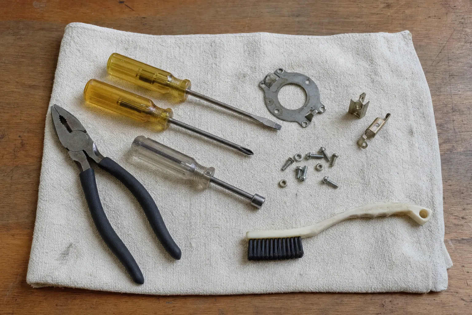 Two amber screwdrivers, a clear nut driver and lineman pliers with a round flange plate, two spring clips and a white brush